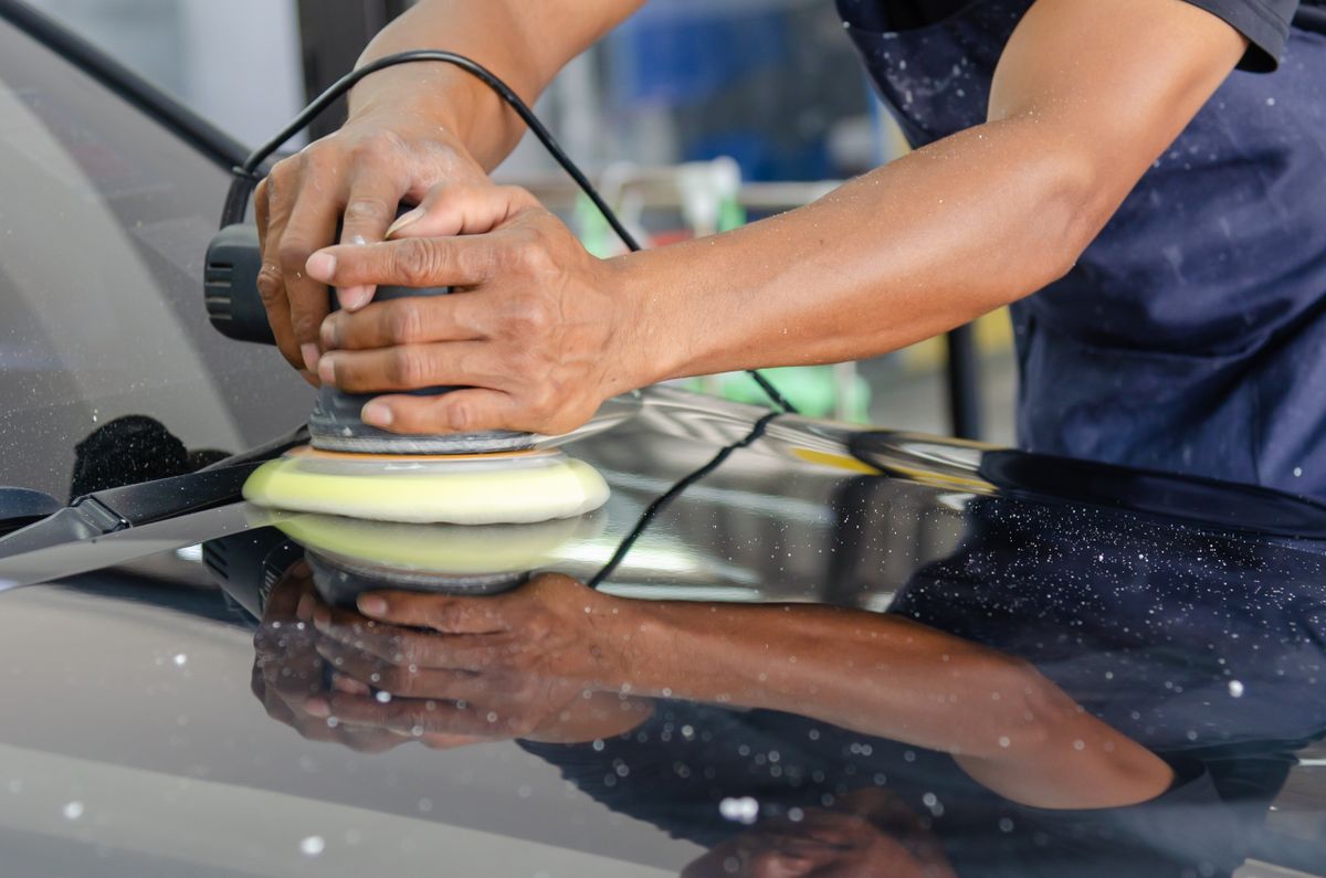 Close-up of a polishing machine working across a car bonnet